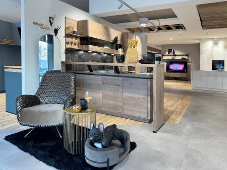 Schicker Wohnraum mit gemustertem Sessel und Holzküche, akzentuiert durch einen schwarzen, flauschigen Teppich und Ananas-Dekor.